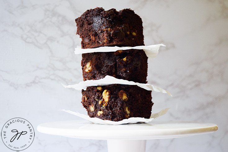 Three oat flour brownies stacked up with pieces of cut parchment paper between them.