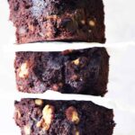 A close up shot of three oat flour brownies stacked up on a white background.