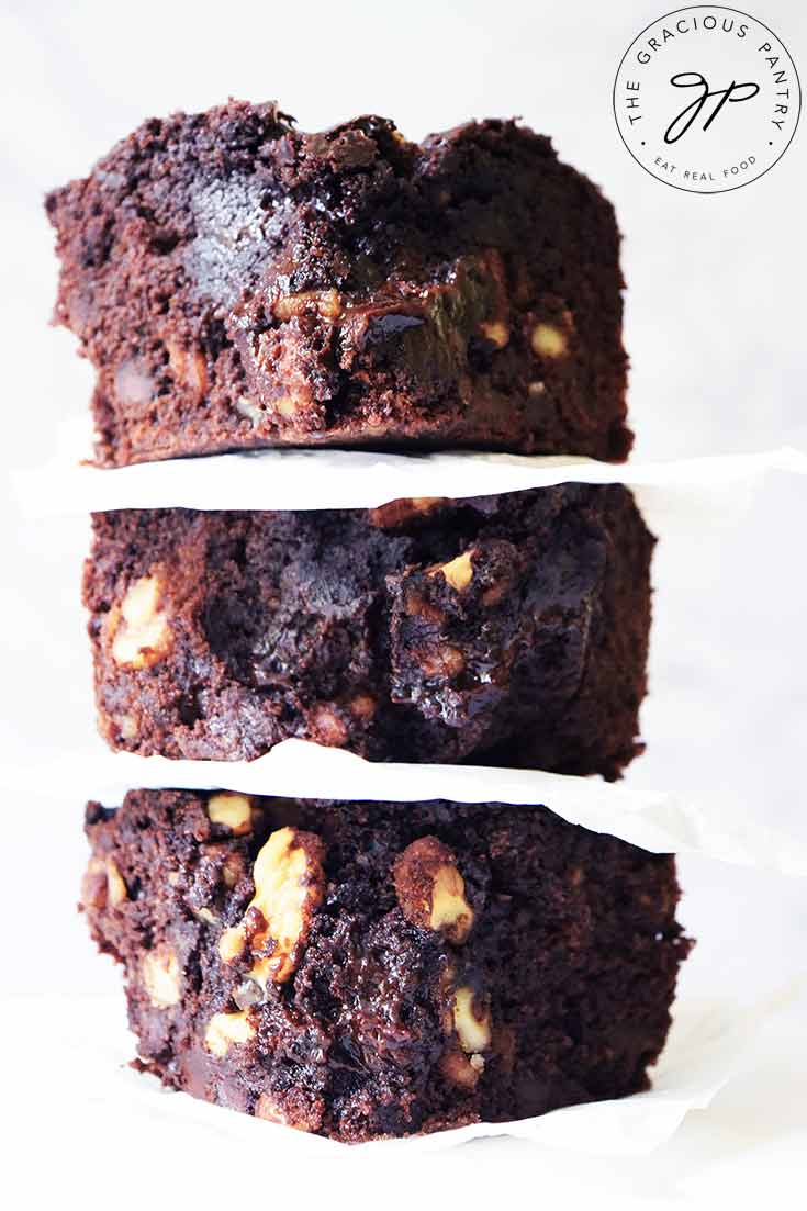 A close up shot of three oat flour brownies stacked up on a white background.