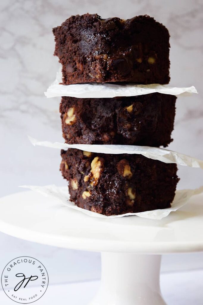 Three oat flour brownies stacked up on a cake stand.