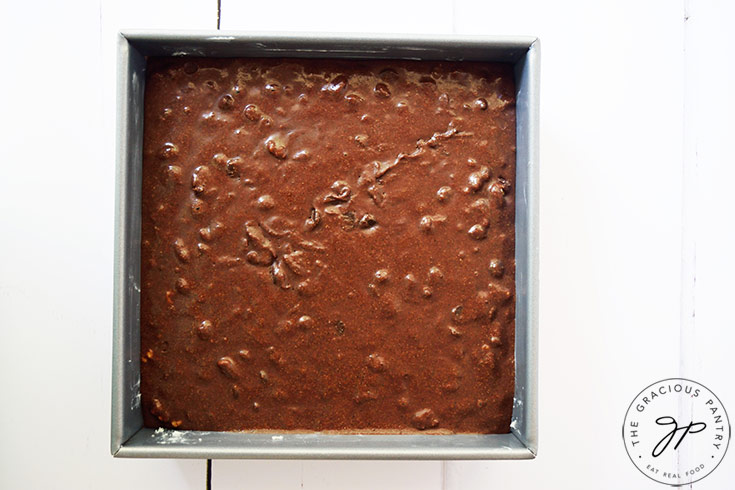 Oat flour brownie batter poured sitting in a square cake pan.