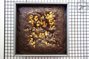 Just baked brownies in a square cake pan, cooling on a black, wire, cooling rack.