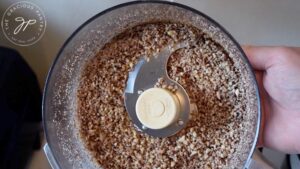 Ground pecans sitting in a food processor.