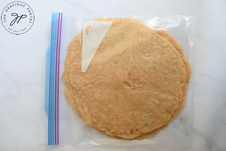 A stack of red lentil wraps inside a clear, zipper-top, plastic bag for storage.