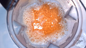 Red lentils and water sitting in a blender tumbler.