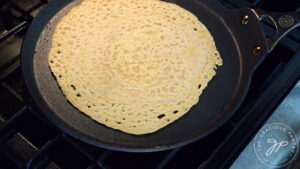 A red lentil wrap cooking on a skillet.