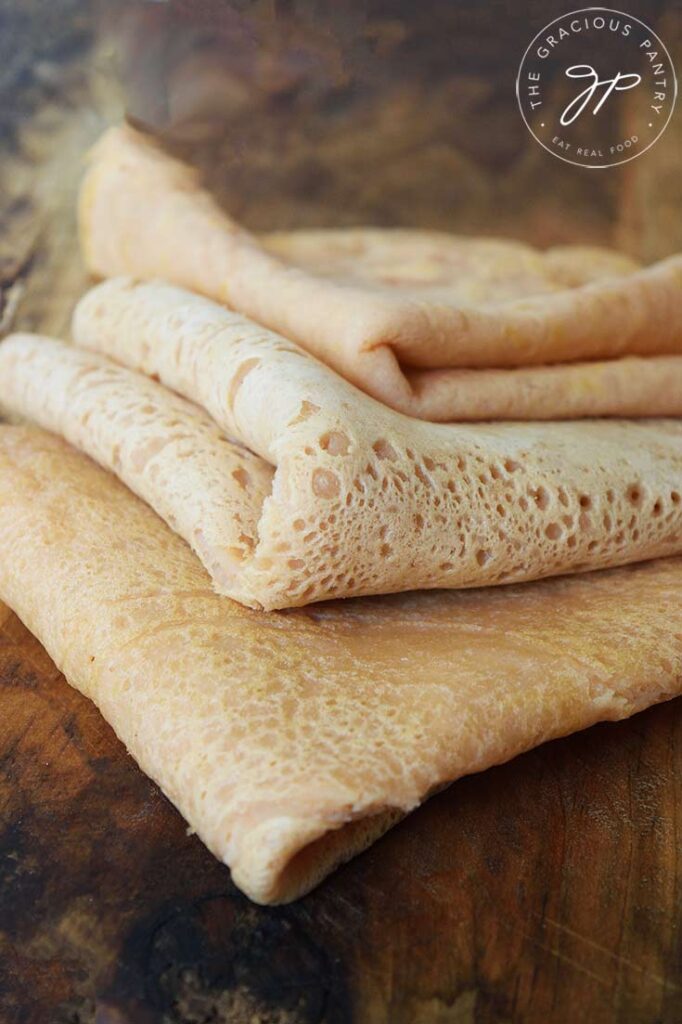 An up close shot of red lentil wraps staggered in a layer on a wooden cutting board.