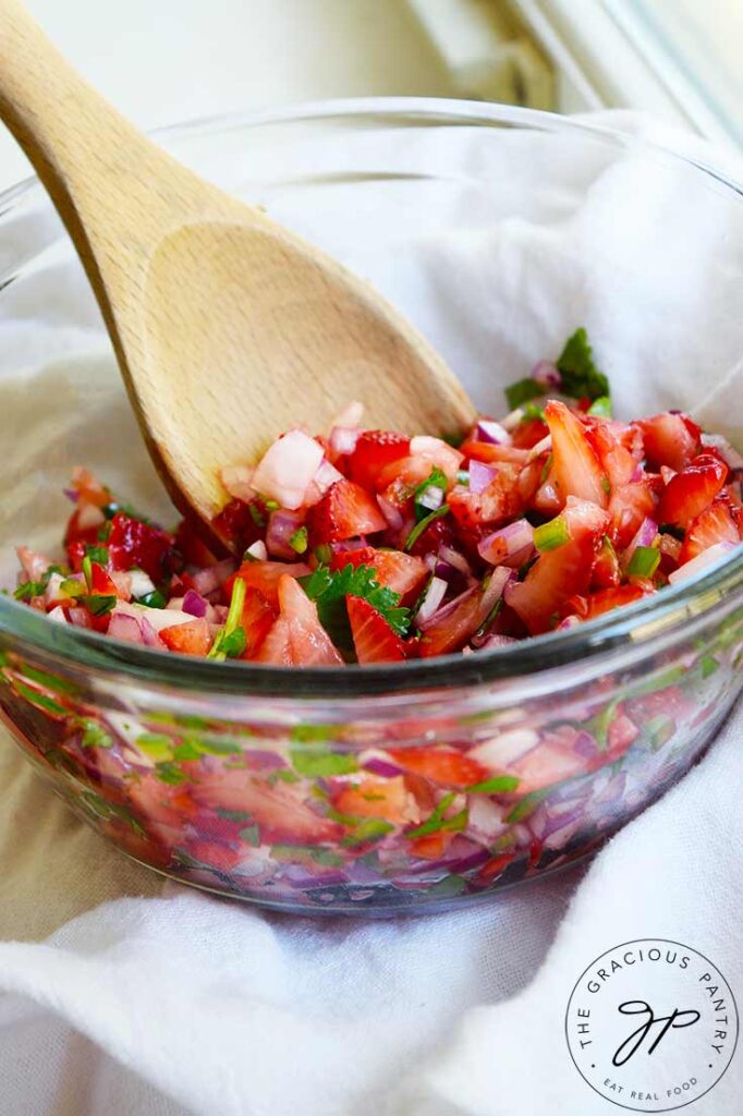 Side view of a glass bowl filled with strawberry salsa.