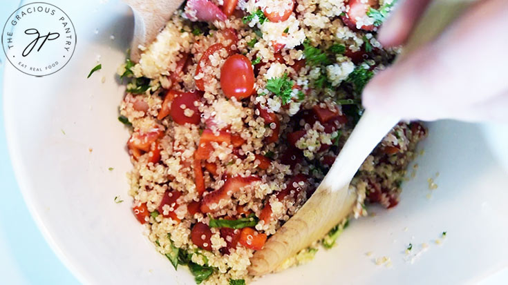 Two wooden spoons tossing the Summer Quinoa Salad.