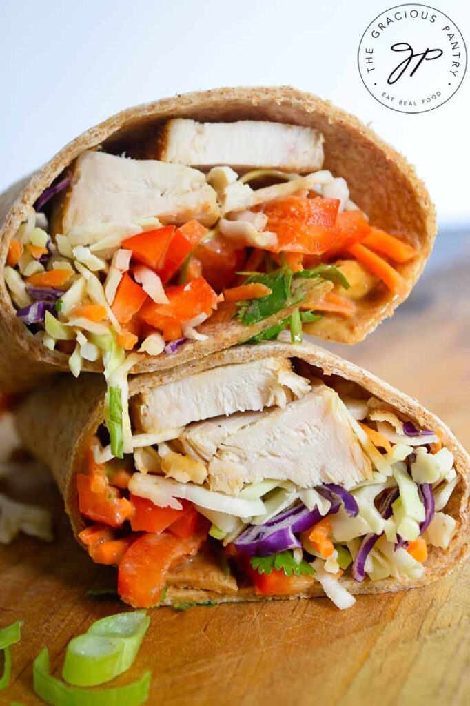 A sliced Thai Peanut Chicken Wrap on a cutting board against a white background.