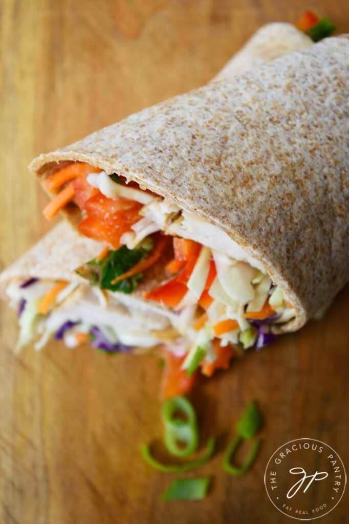 And overhead view looking down on a silced Thai Peanut Chicken Wrap sitting on a cutting board.