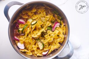 Bow Tie Pasta Salad sitting in a pot on a white background.