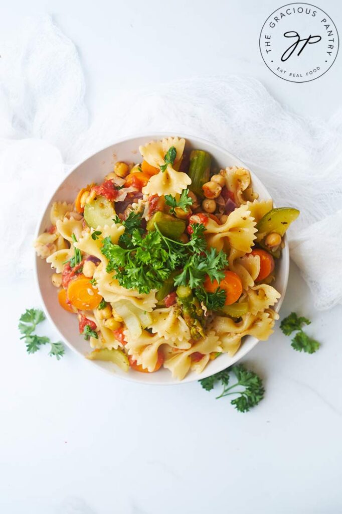 An overhead view looking down into a white bowl filled with Bow Tie Pasta Salad.