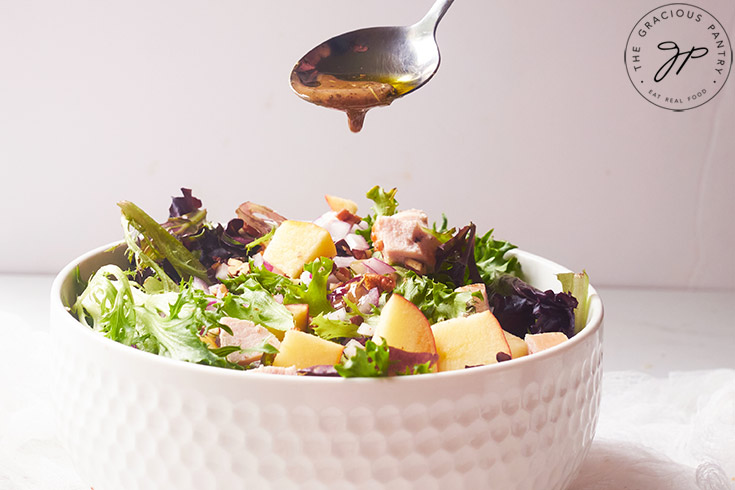 A bowl of salad having dressing spooned over the top.