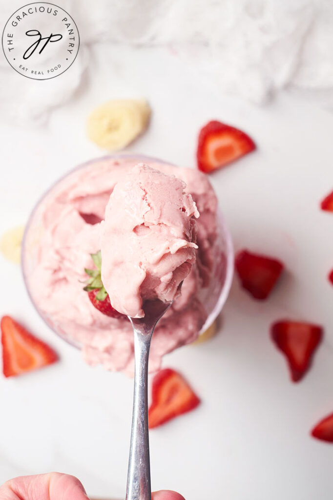 A spoon holds a spoonful of Healthy Strawberry Ice Cream.