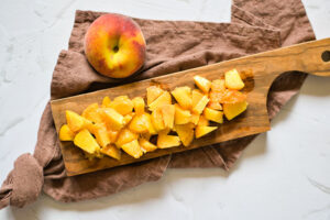Chopped peaches sitting on a cutting board.