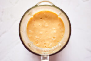 Blended Homemade Peach Popsicles Recipe ingredients sitting in a blender tumbler.