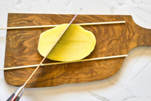 Chopsticks on a potato slice demonstrates how to cut accordion potatoes.