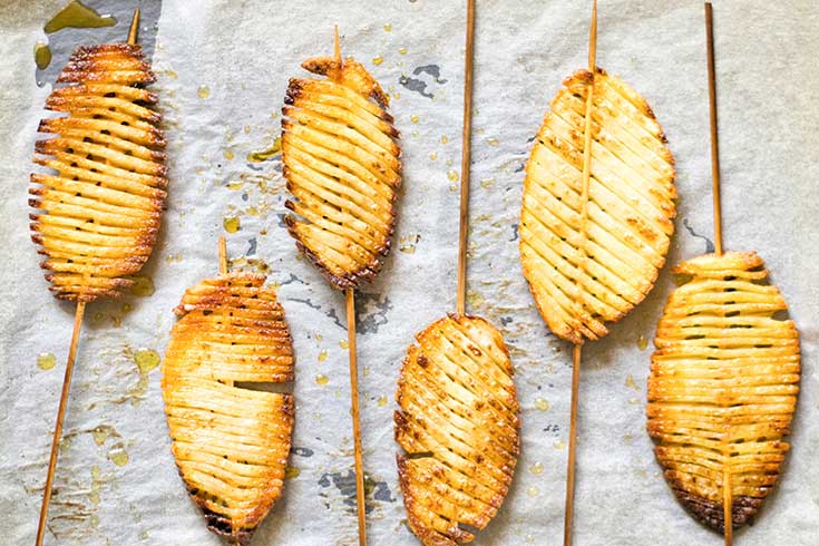 Baked accordion potatoes on a parchment-lined cookie sheet.