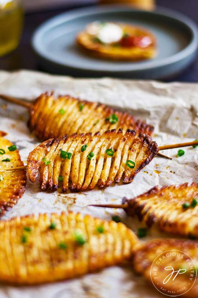 Accordion potatoes lay on a parchment-lined cookie sheet.