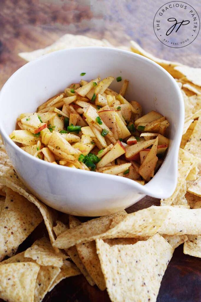 Apple salsa in a white serving bowl with corn chips laying around the base of the bowl.