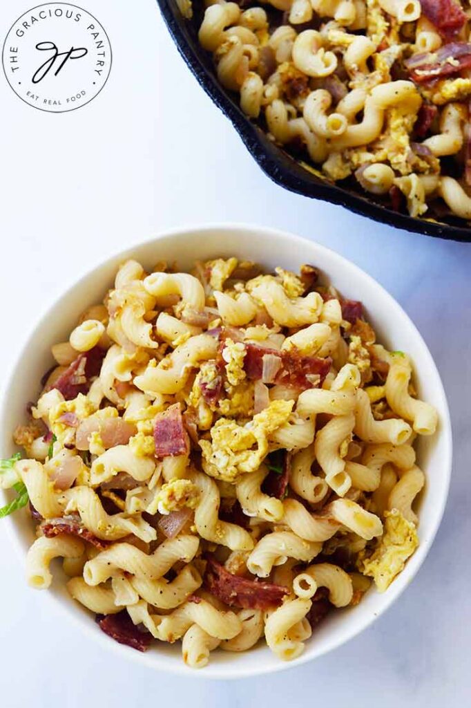 An overhead view looking down into a white bowl filled with breakfast pasta.