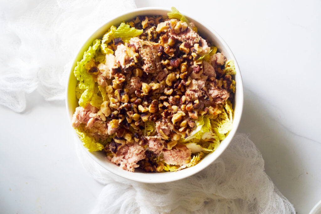 An overhead view of a white bowl filled with chicken endive salad.