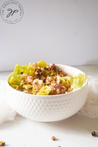 A white bowl on a white surface, filled with Chicken Endive Salad.