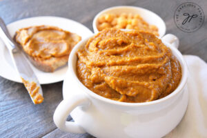 Sweet pumpkin hummus in a white bowl. Toast sits behind it.