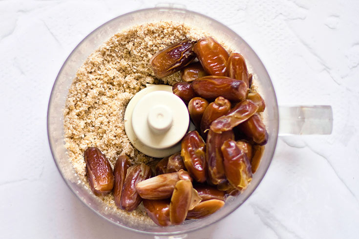 Dates added to already blended Gluten-Free Carrot Cake crust sitting in a food processor.