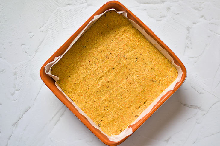 Gluten-Free Carrot Cake dough pressed into a parchment-lined, square baking pan.