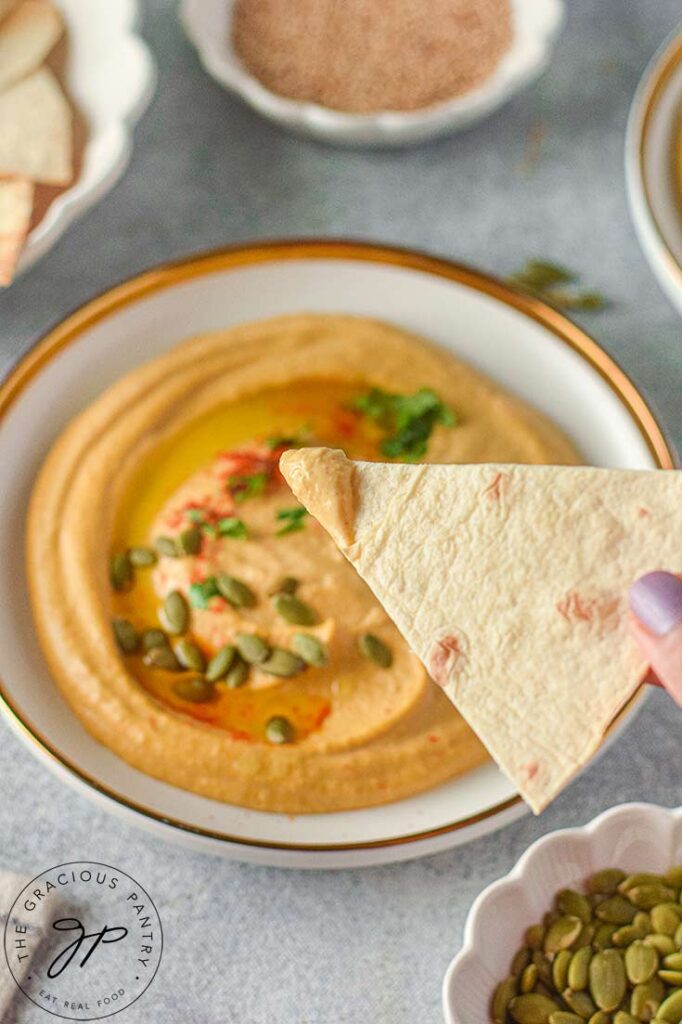 A chip holds some pumpkin hummus towards the camera.