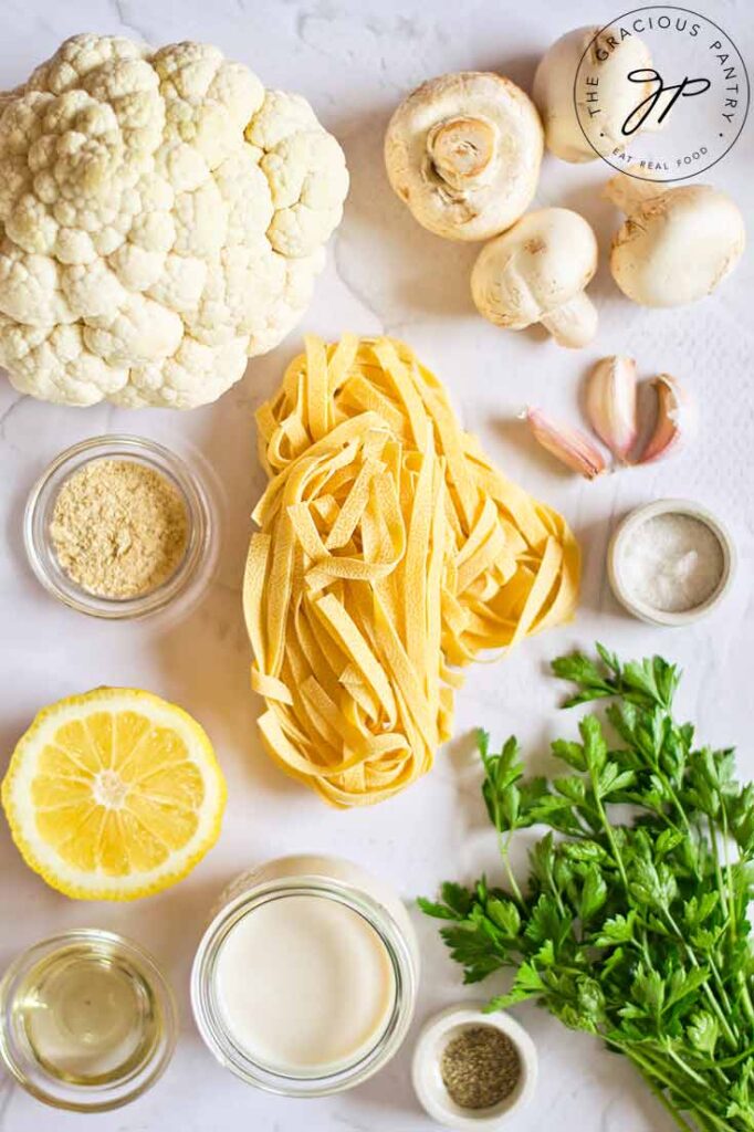 All the ingredients for this vegan fettuccine alfredo recipe collected and placed on a white surface.