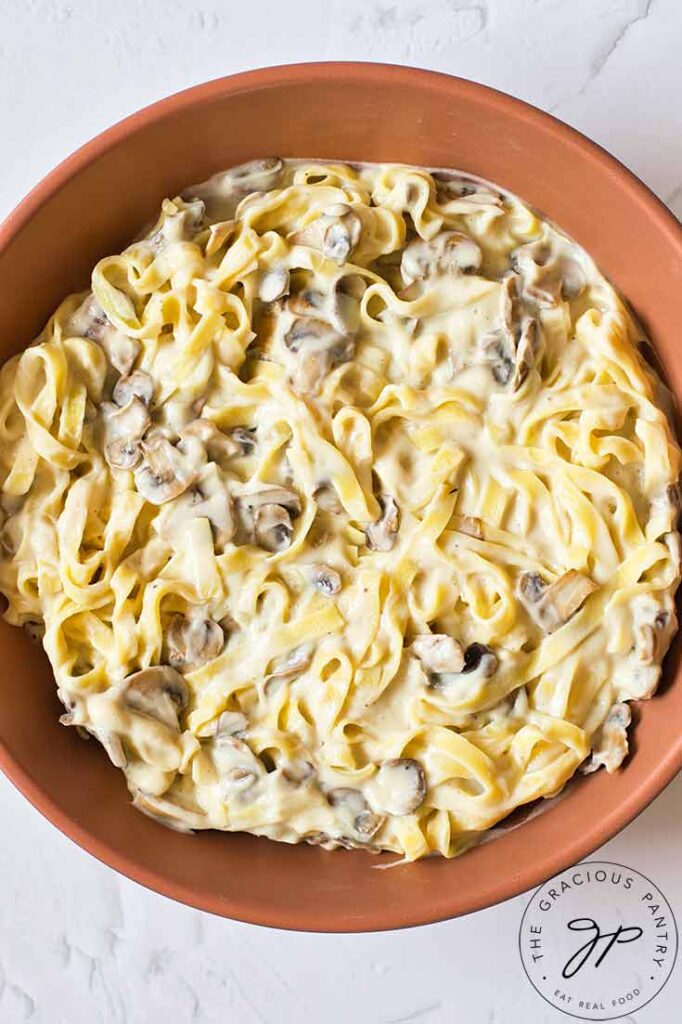 Just combined fettuccine alfredo sitting in a skillet.