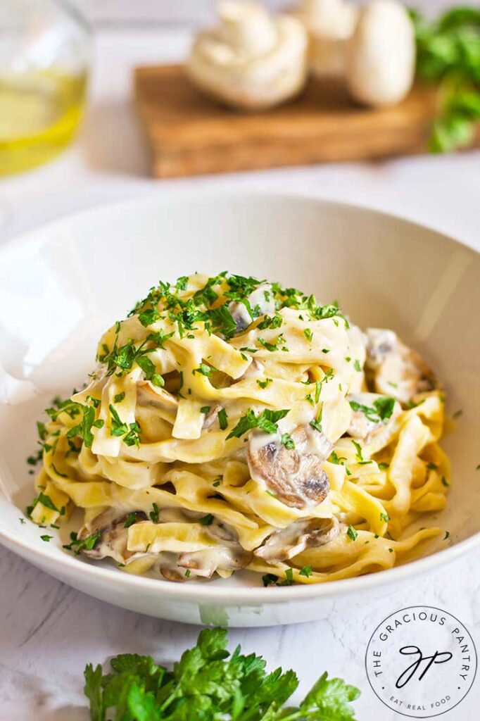 Vegan Fettuccine Alfredo served in a white bowl and garnished with fresh parsley.