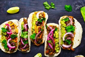 Mushroom Tacos lined up on a dark background.