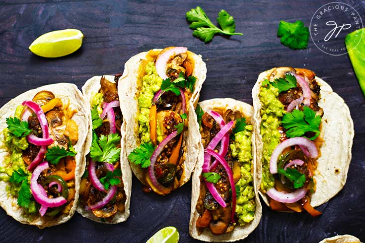 Mushroom tacos lined up on a dark background.