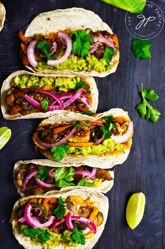 Prepared mushroom tacos, lined up vertically on a dark surface.