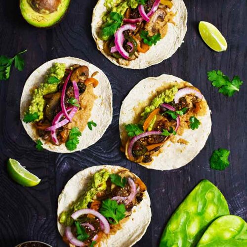 Prepared mushroom tacos laid out flat on a dark surface.