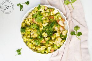 Chicken Vegetable Salad ingredients mixed together and served in a white, fluted dish.