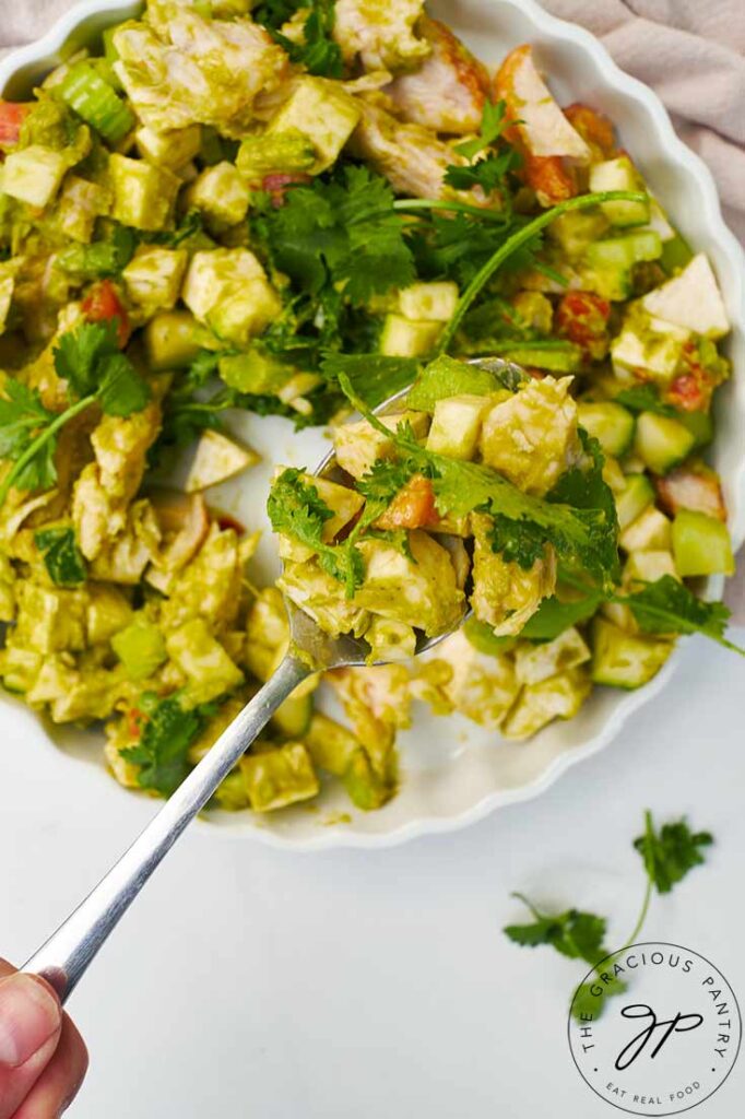 A spoon lifts some Chicken Vegetable Salad towards the camera.