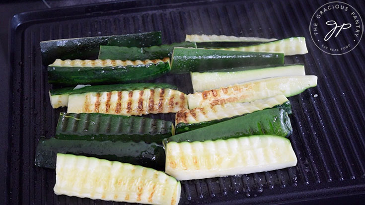 Slices of zucchini cooking on a grill.