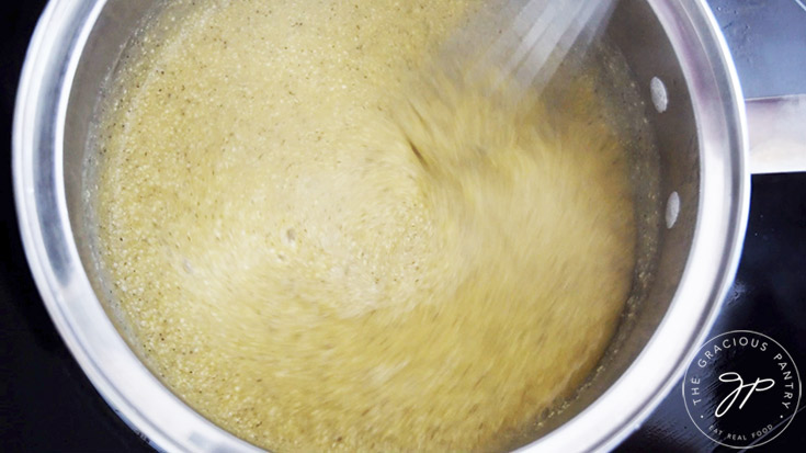 Whisking grits in a pot.
