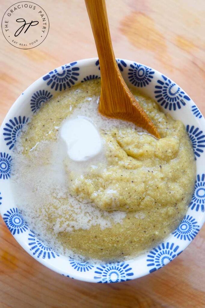 A small bowl of millet grits served in a decorative bowl with pat of butter on top.