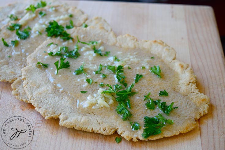 Oat flour flatbread topped with melted garlic butter and fresh parsley.