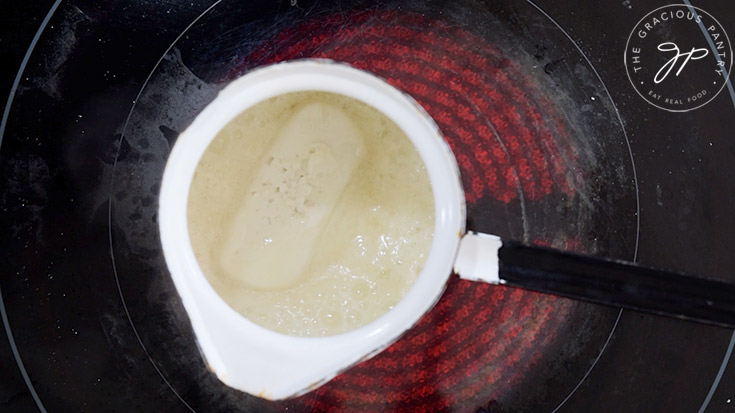 Butter melting in a small, white pot.