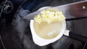 Chopped garlic being added to simmering, melted butter.