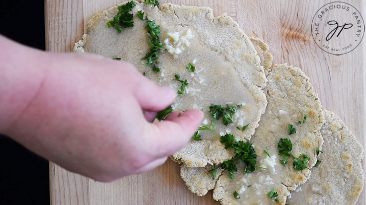 Sprinkling freshly chopped parsley over oat flour flatbread.