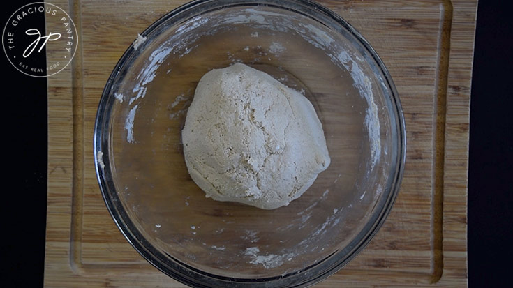A ball of oat flour flatbread dough sitting in a glass mixing bowl.