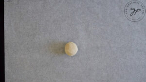 A walnut-sized ball of oat flour flatbread dough sitting on a piece of parchment.